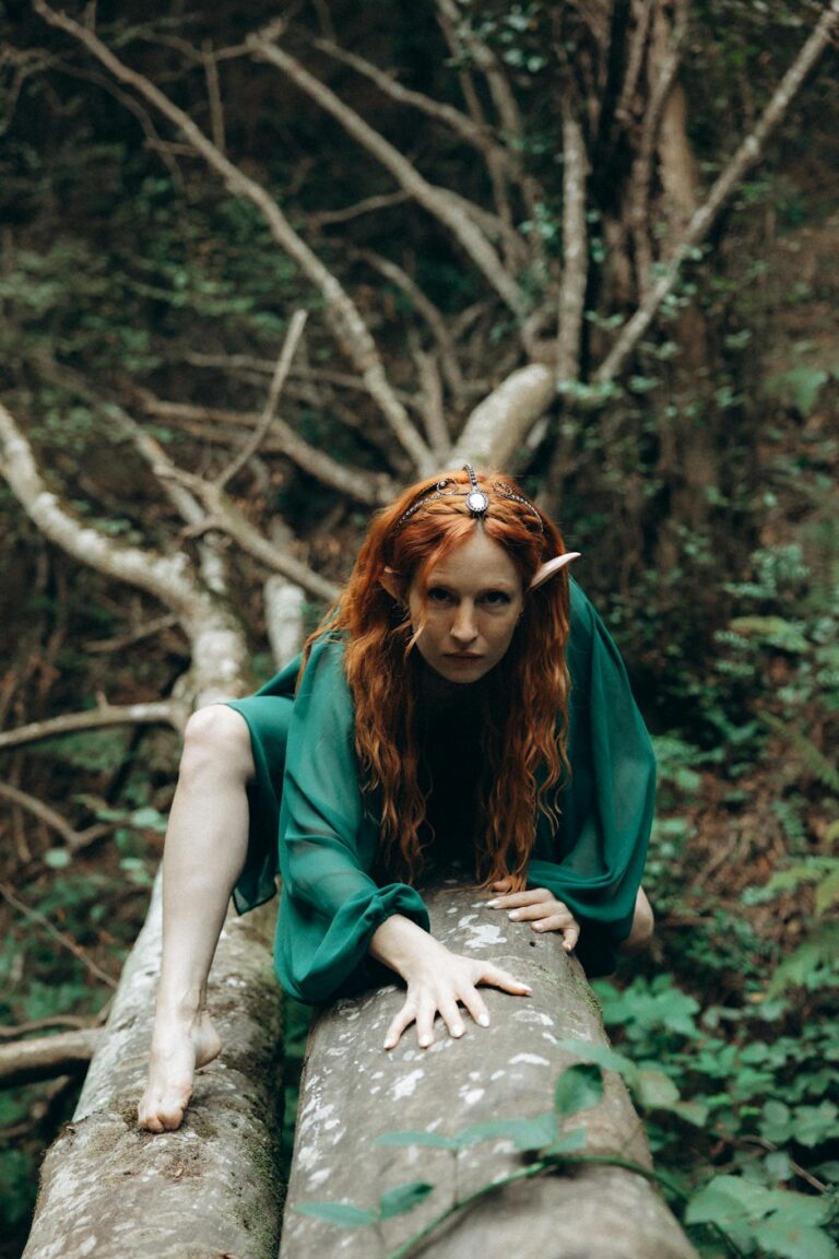 A woman with red hair is sitting on a tree branch